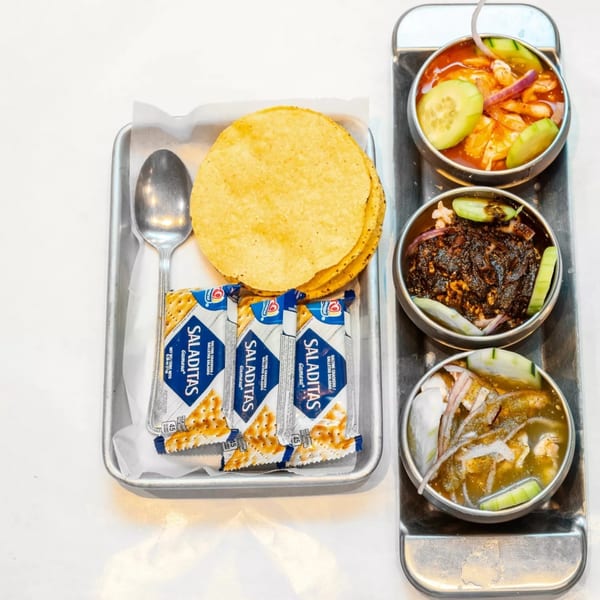 Three bowls of seafood ceviche, crackers, and tostadas on a metal tray at Cajun Crab & Shrimp.