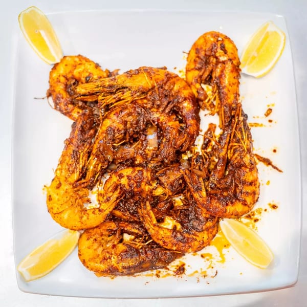 Cajun Crab & Shrimp Bar & Grill's spicy Cajun shrimp, garnished with lemon wedges on a white plate.