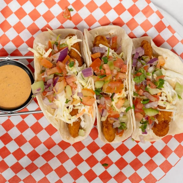Three Cajun Crab & Shrimp Bar & Grill fish tacos with salsa, cabbage, and sauce.