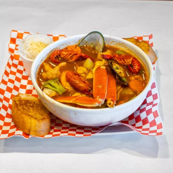 Cajun seafood boil with crab, crawfish, mussels, and vegetables in a bowl with rice and toast.