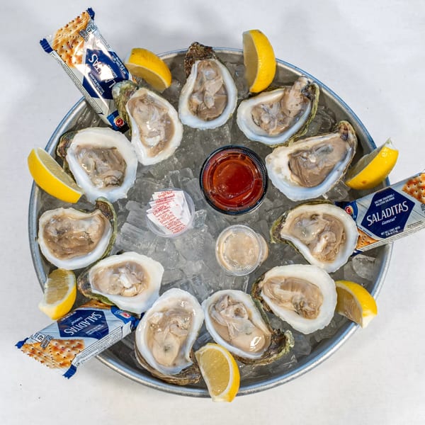 A dozen fresh oysters on the half shell, served on ice with lemon wedges, cocktail sauce, and crackers.